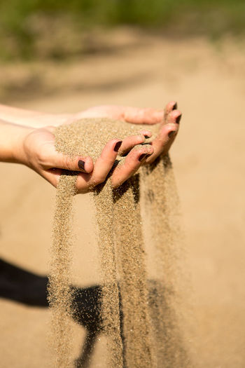 Midsection of person holding hands on sand at beach