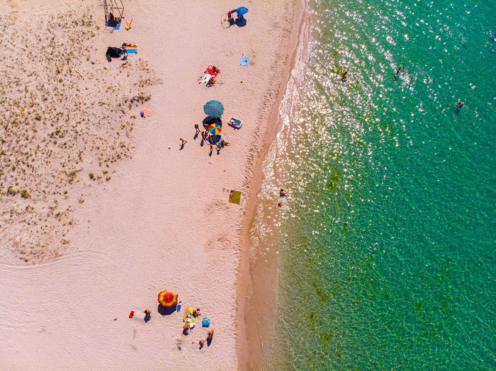 Aerial view of a sandy beach with people resting and parasols. view from above