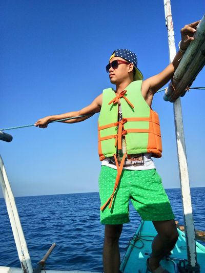 Boy wearing sunglasses against sea against clear sky