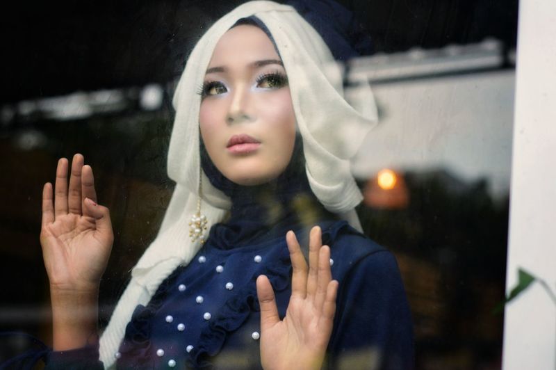 Woman in hijab seen through glass window