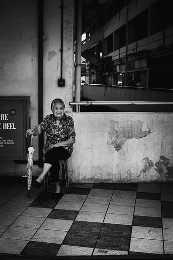 Senior woman with umbrella sitting in corridor