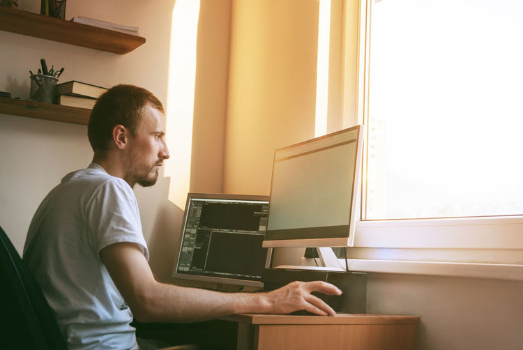 Side view of man working on laptop at home