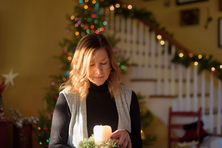 Mature woman holding illuminated candle at home during christmas