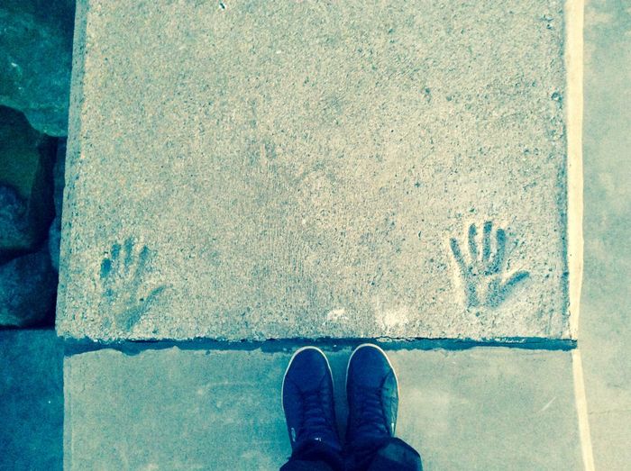 Low section of man standing by handprint on pathway