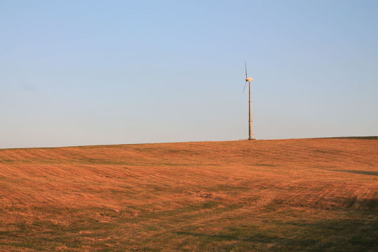 Wind turbines on field against sky