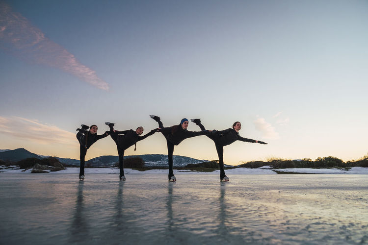 Female figure skaters practicing on frozen lake at dusk