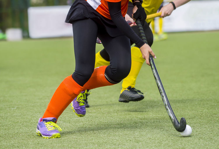 Low section of people playing hockey on field