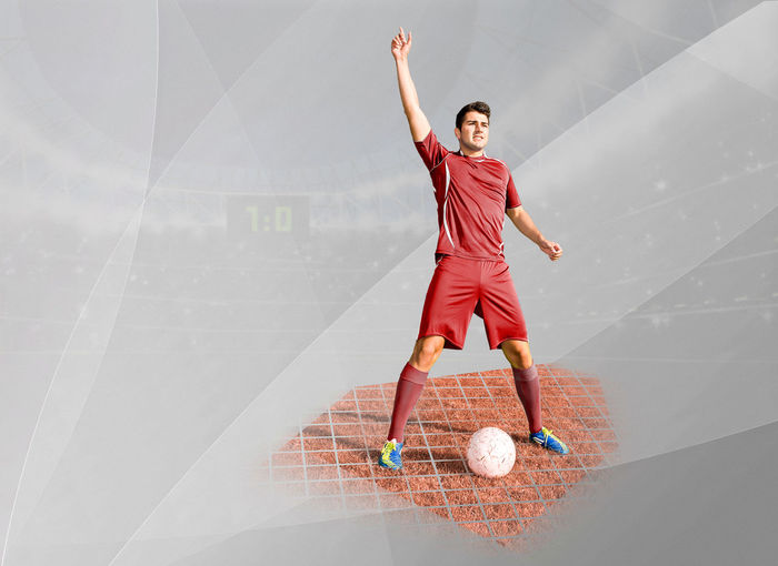 Digital composite image of soccer player with ball standing in stadium