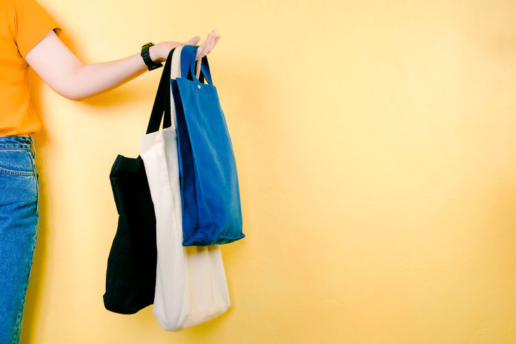 Asian woman shopping by use fabric bag instead of plastic bag with yellow pastel background