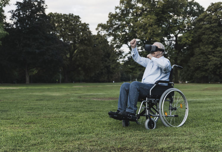Senior man sitting in wheelchair using virtual reality glasses