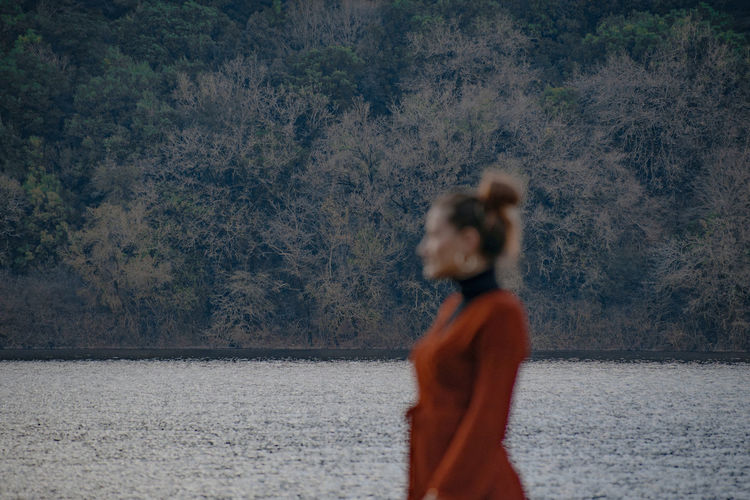 Rear view of young woman standing against lake