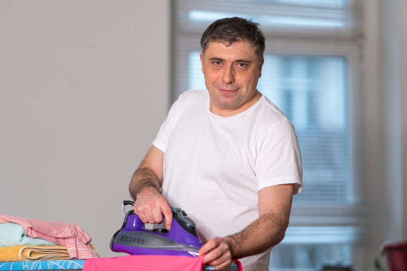Portrait of man ironing cloth at home