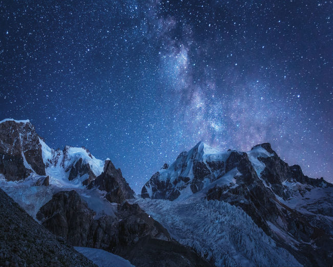 Scenic view of snowcapped mountains against sky at night