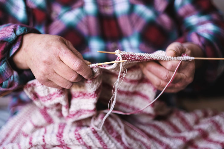 Close up of senior woman hands knitting sweater for her grandson. authentic lifestyle of love, life