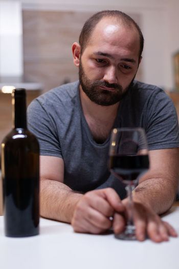 Depressed man drinking wine while sitting at home