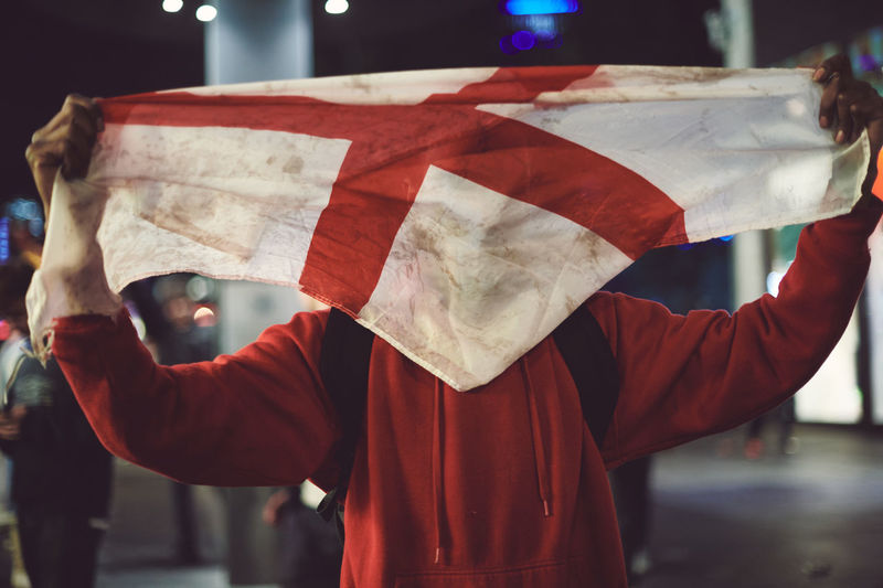 Midsection of person holding up england flag