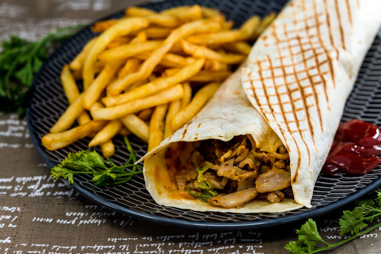 Close-up of fajita and french fries in plate on table