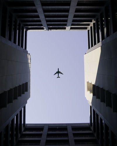 Directly below shot of airplane and buildings against clear sky