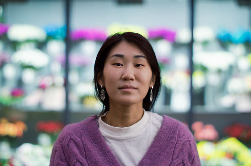 Portrait of a young asian woman looking at camera on background of blurred flower shop