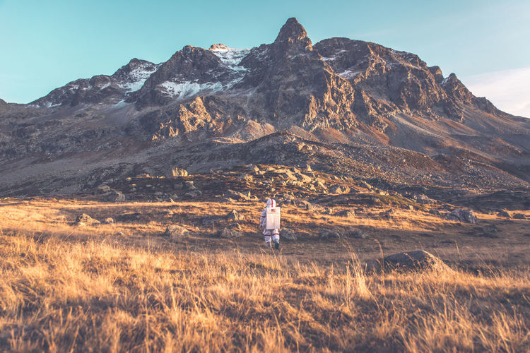Astronaut standing on land against mountain