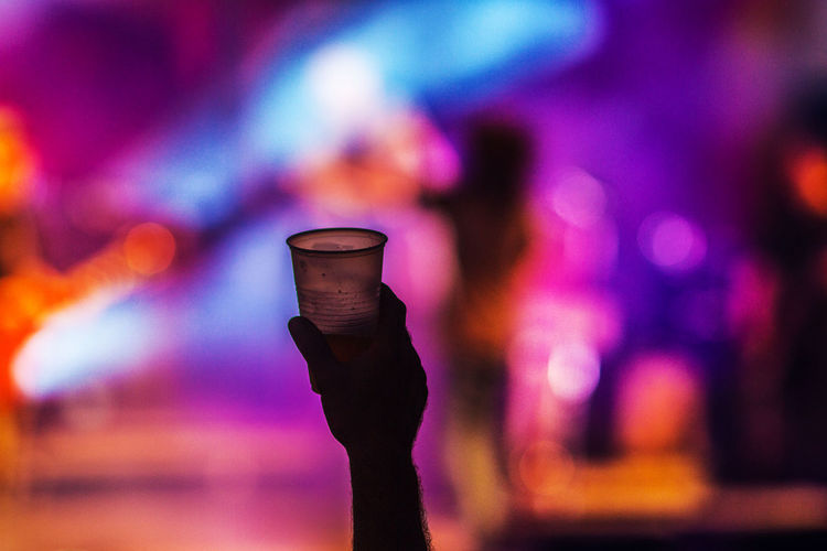 Cropped image of hand holding drink in glass at music festival