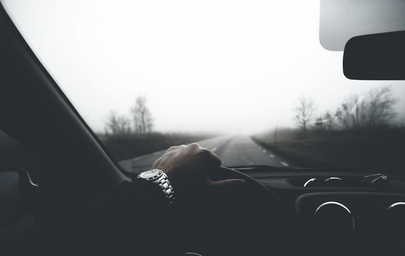 Cropped image of man hand on steering wheel in car