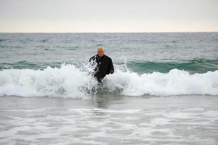 Man wading in sea against sky