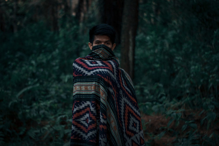 Man standing by plants in forest