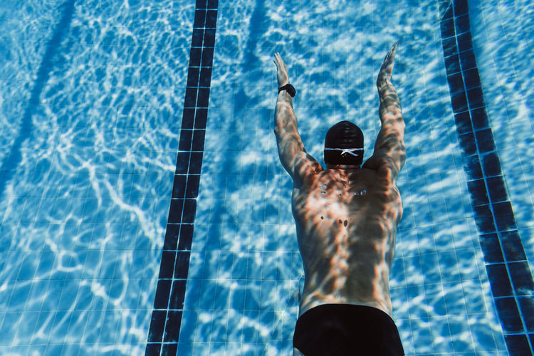Young man gliding underwater after diving into pool