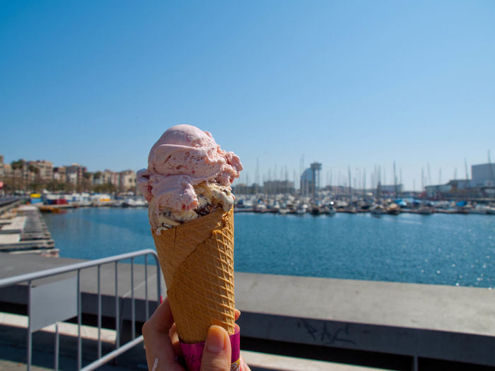Man holding ice cream cone against sky