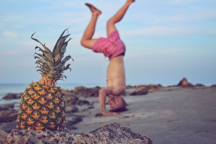 Balancing on head eith pineapple on beach