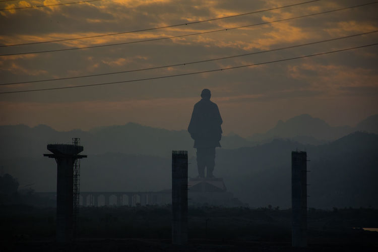 Silhouette man standing by mountain against sky during sunset