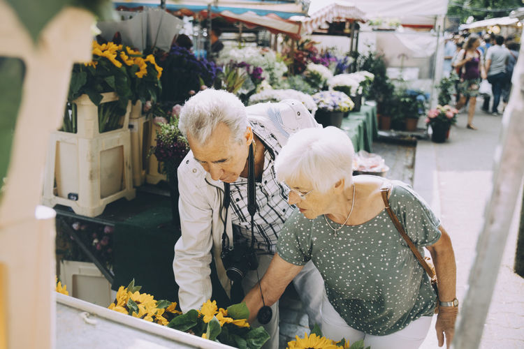 Senior couple shopping for flowers at market in city during vacation