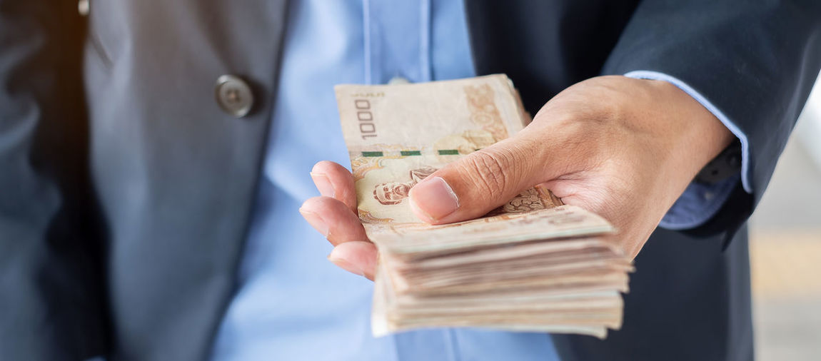 Midsection of businessman holding paper currencies