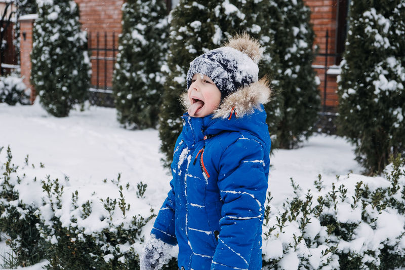Stop kids from eating snow. outdoor winter portrait of little boy with tongue hanging out eating