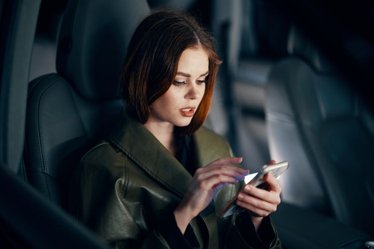 Young woman using mobile phone while sitting in car