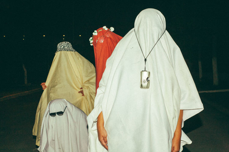People wearing costume standing outdoors at night