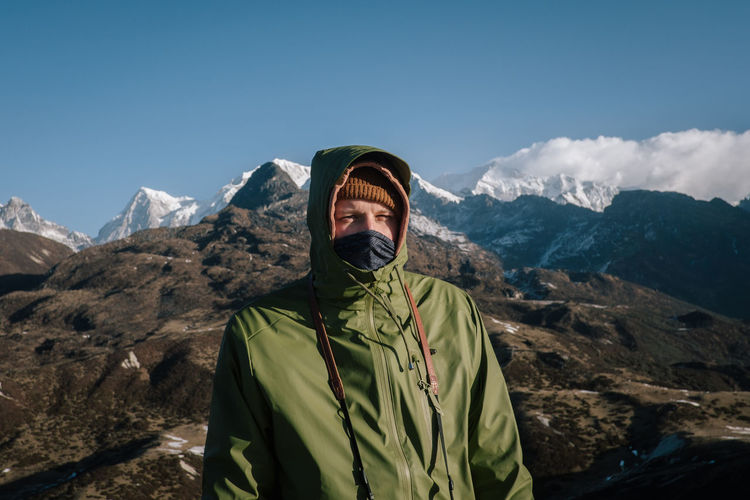 Portrait of man standing by mountains against sky