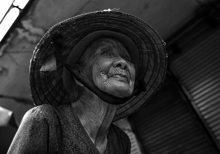 Close-up low angle view of senior woman wearing asian style conical hat outdoors