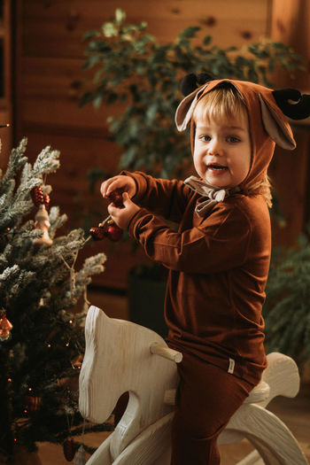 Toddler baby boy in rudolph reindeer costumes decorating christmas tree christmas tree