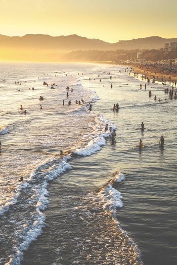 People at beach against sky during sunset