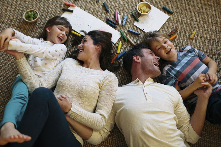 Overhead view of happy parents with children lying on carpet at home