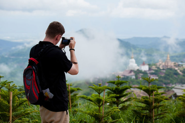 Rear view of man photographing while standing on mountain