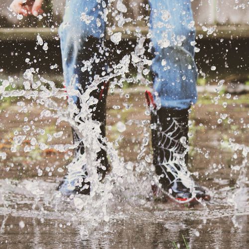 Low section of child jumping in puddle