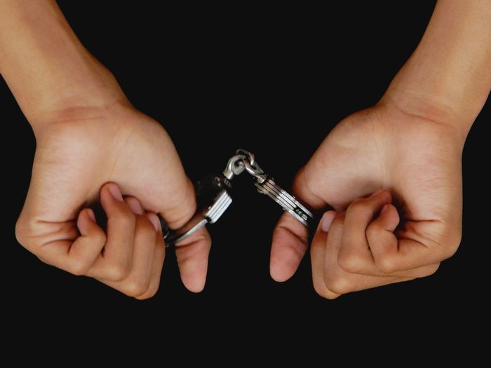 Close-up of man with small hand cuffs over black background