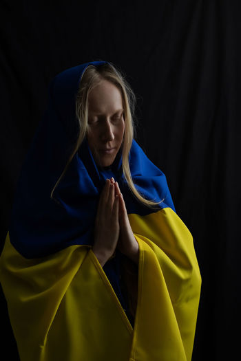 Woman with flag praying, god save ukraine