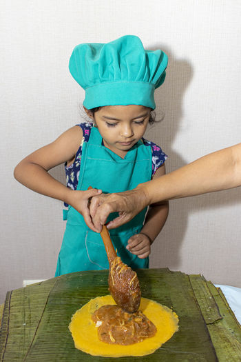 Cropped hand of person and girl holding food while standing by table