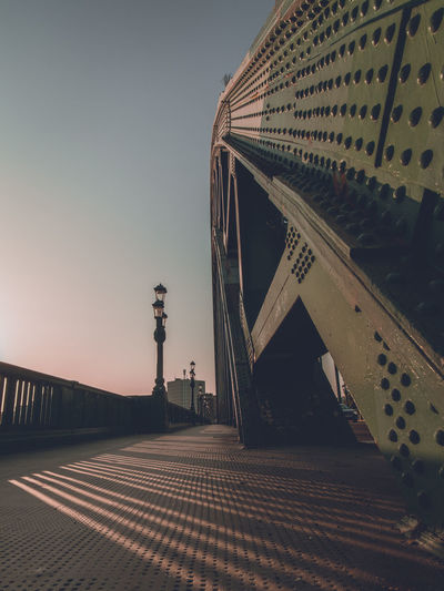 Low angle view of bridge against buildings during sunset
