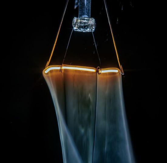 Smoking filament. a broken light bulb. close-up of illuminated light bulb against black background