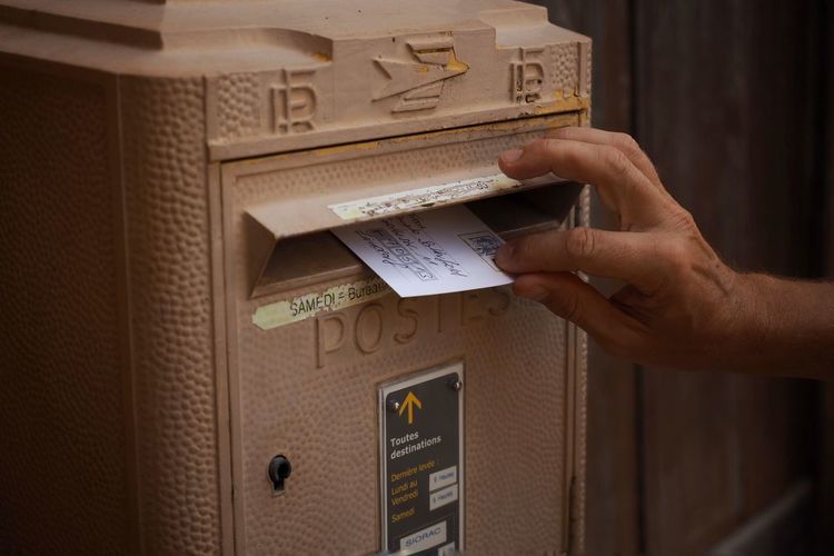 Cropped hand inserting postcard in mailbox